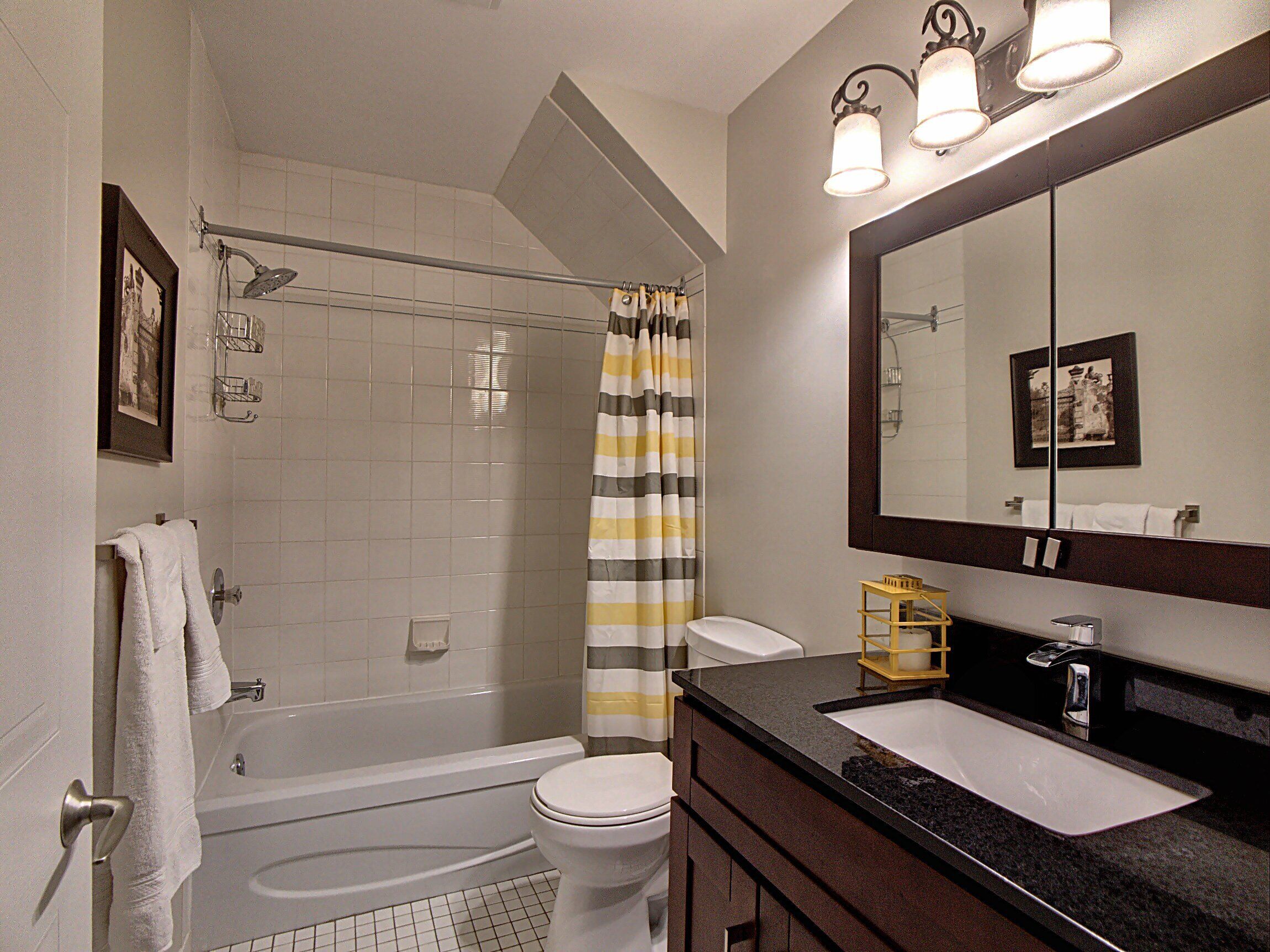 A bathroom with a bathtub, toilet, and a sink with a mirror.