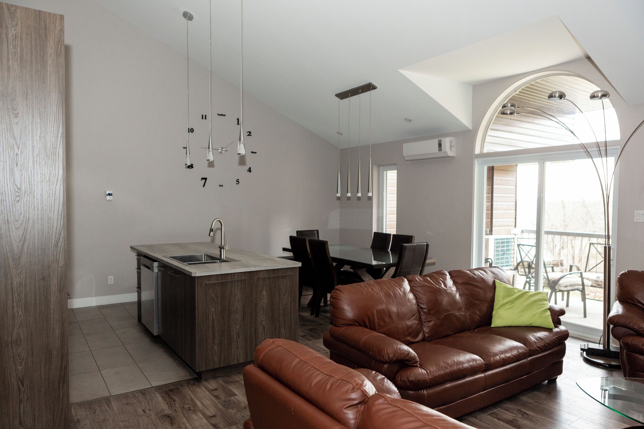 A modern living space with a kitchen island, dining area, and a leather sofa.