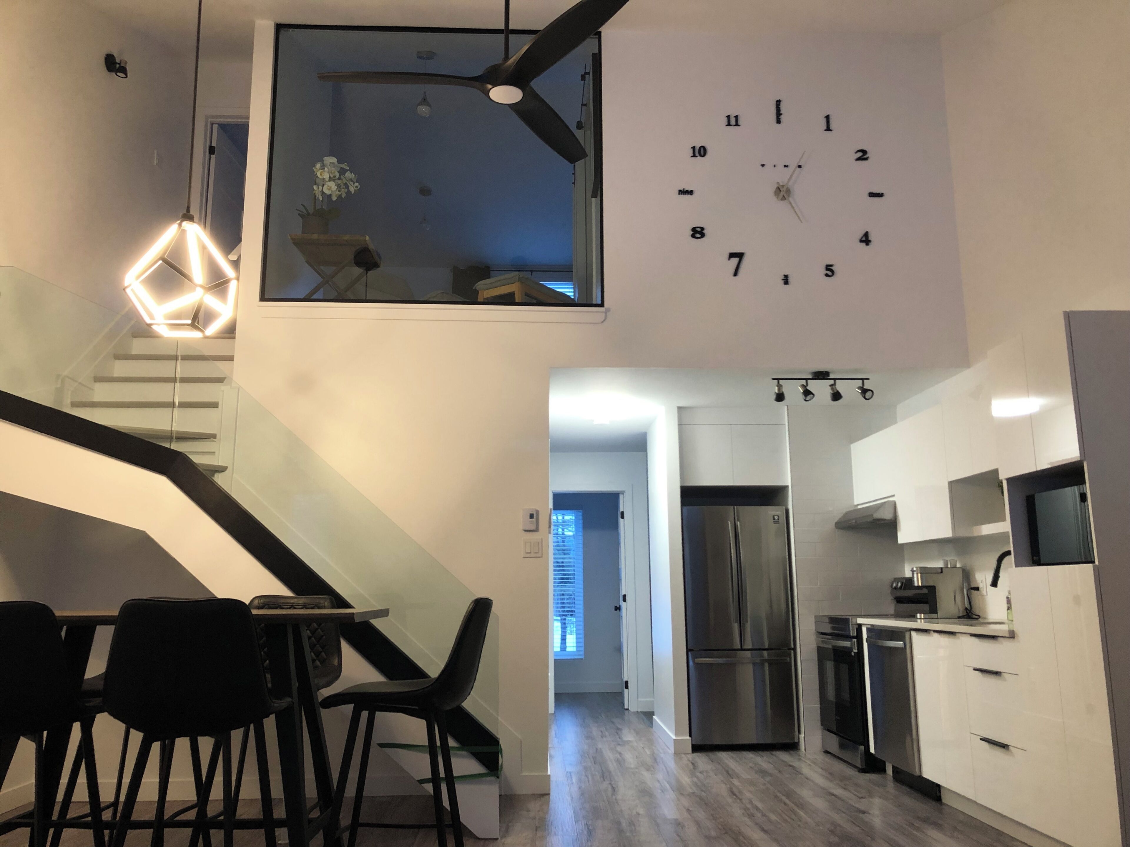 A modern kitchen with a stainless steel refrigerator, white cabinets, and a dining area with a table and chairs.