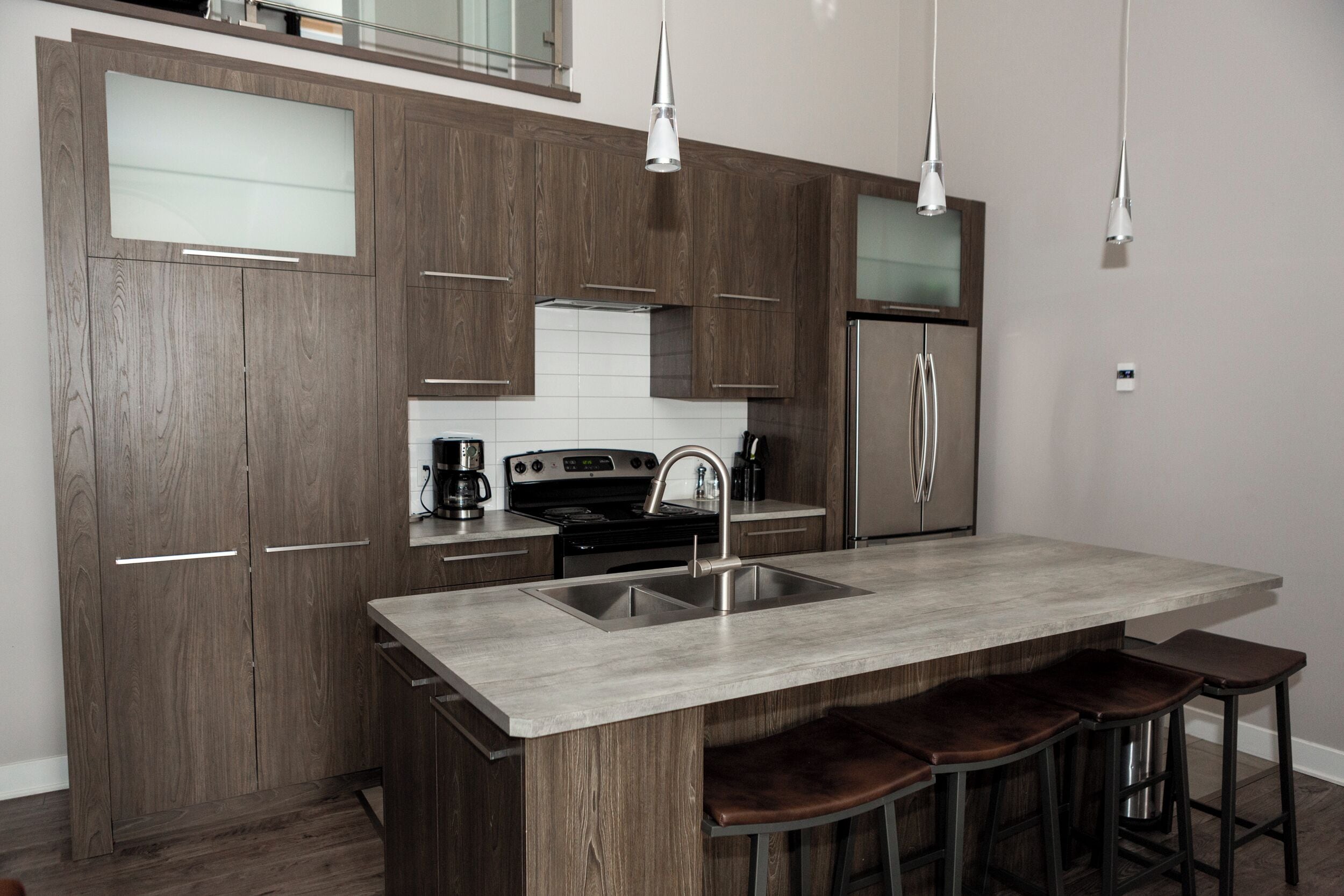 A modern kitchen with a central island, stainless steel appliances, and wooden cabinetry.