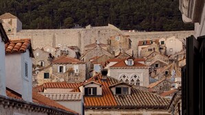 Un pueblo histórico con edificios de piedra, techos de teja y un telón de fondo montañoso.