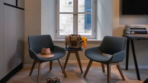 Una sala de estar moderna con dos sillones, una mesita, un sofá, un televisor y una ventana con persianas.