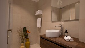 Un baño moderno con un espejo grande, un lavamanos redondo y un mueble de tocador de madera.