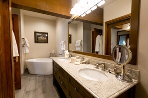 Bathroom features a bathtub, two sinks, and a large mirror.