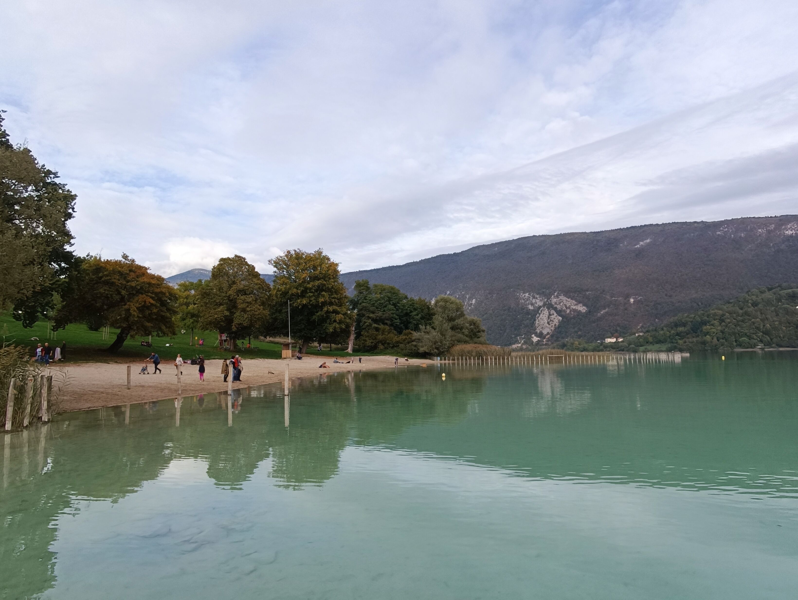Un cadre paisible au bord d’un lac, avec une eau limpide, entouré d’arbres et de collines.