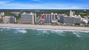 Um hotel costeiro com vários edifícios altos, praia e vista para o oceano.