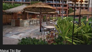 Un bar tiki con asientos al aire libre y una estructura de techo de paja.