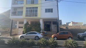 Un edifici de diverses plantes amb teulada plana, un balcó al segon pis i una entrada tancada per reixa.