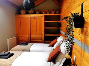 Ein gemütliches Schlafzimmer mit einem hölzernen Kleiderschrank, einem Bett mit weißer Bettwäsche und einer hängenden Pflanze.