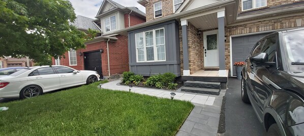 A residential house with a garage, a driveway, and a well-maintained lawn. - Luxury Private Suite (Brampton)