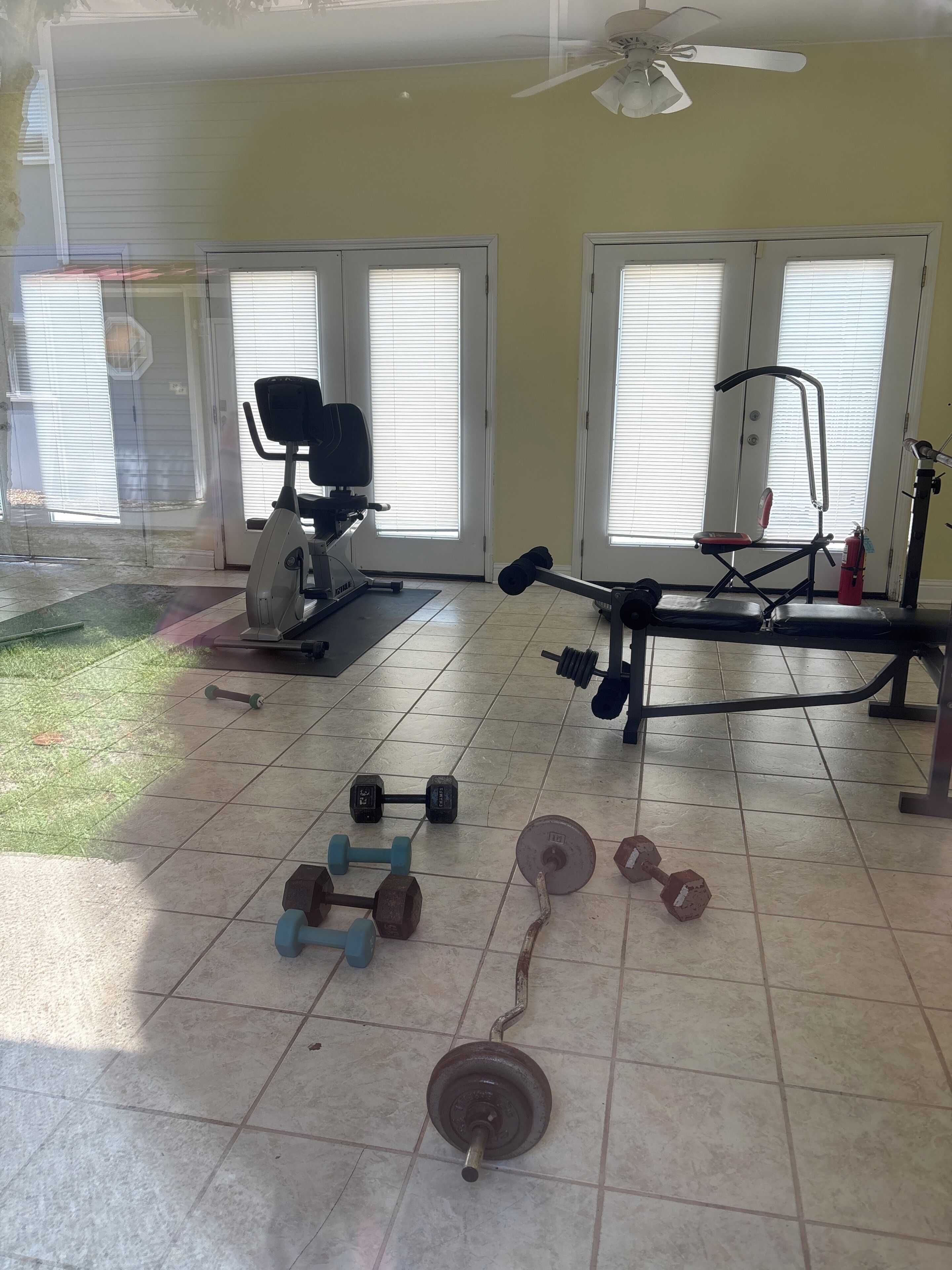 A home gym with exercise equipment, including dumbbells, a bench press, and a stationary bike.