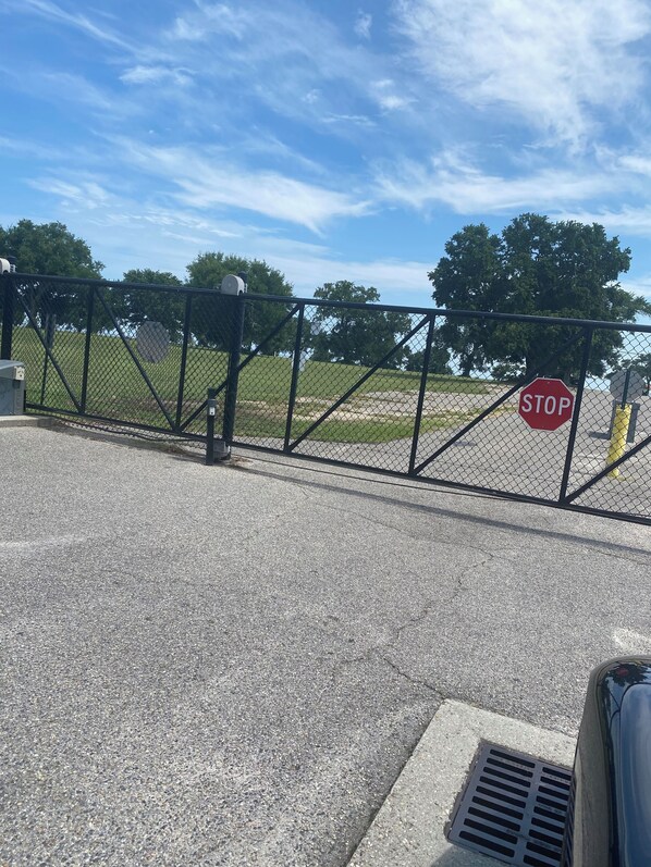 A gated area with a stop sign, a metal fence, and a grassy field in the background.