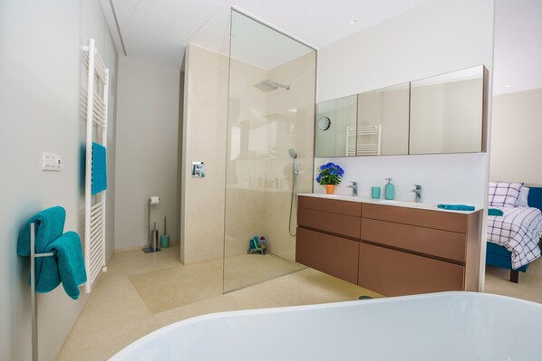 Un baño moderno con cabina de ducha de vidrio, una bañera blanca y un tocador con espejo.