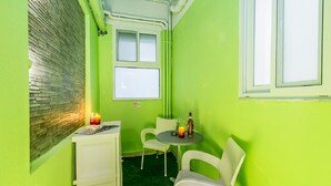 Ein kleiner Raum mit grüner Wand, einem Fenster, einem Tisch mit Stühlen und einem kleinen Schrank.