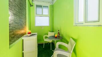 A small room with a green wall, a window, a table with chairs, and a small cabinet.