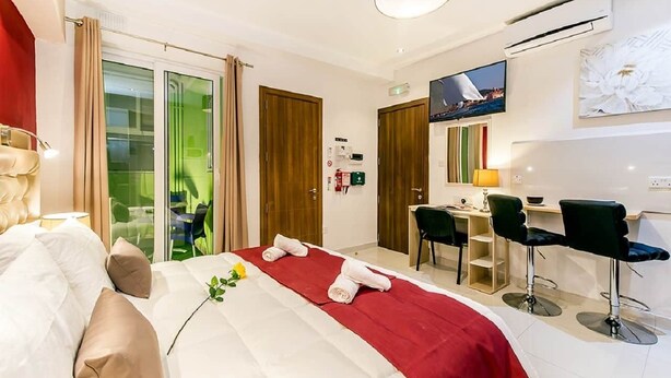 Ein Hotelzimmer mit Bett, Schreibtisch und Fernseher.