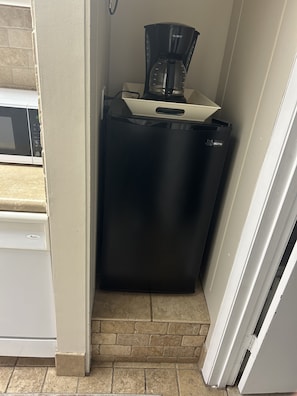 Una cocina compacta con un refrigerador negro, un microondas y una cafetera.