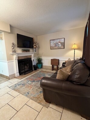 A living room with a fireplace, a sofa, a television, and a lamp.