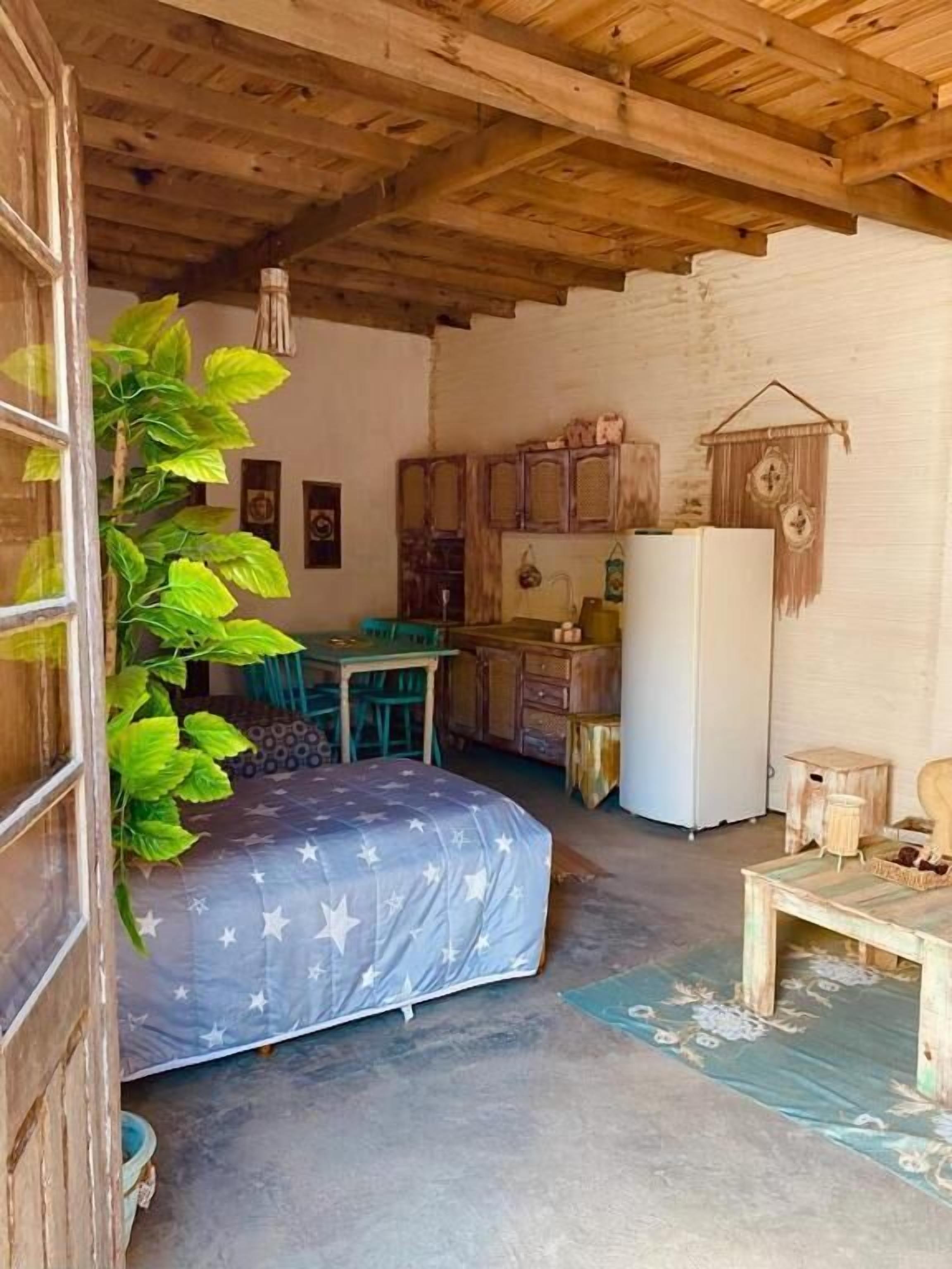 A rustic room with a bed, a desk, and a refrigerator.