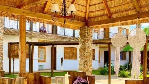 Un salón al aire libre con mobiliario de madera y techo de paja.
