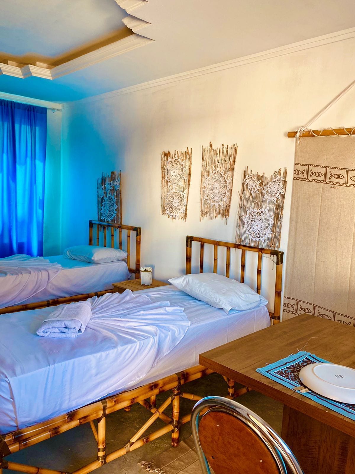 A hotel room with two beds, a wooden table, and a chair.