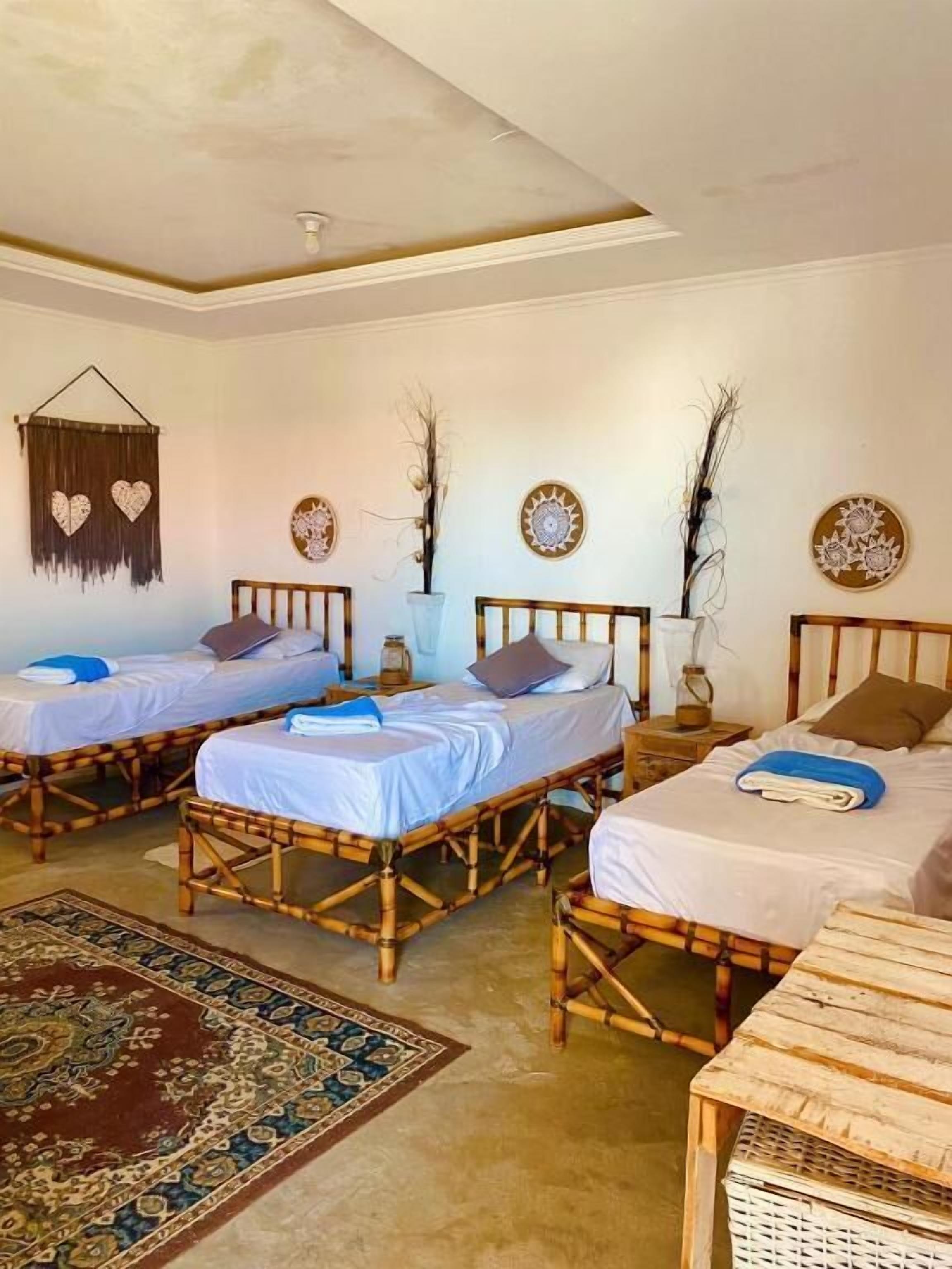 A room with three wooden beds, a woven rug, and decorative wall art.