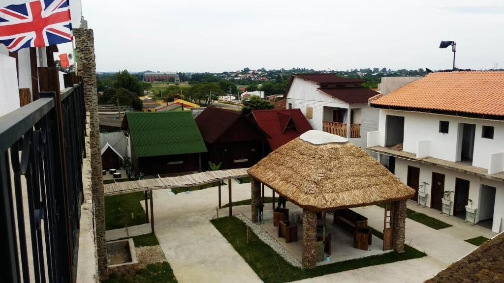 A courtyard with a thatched-roof pavilion, a flag, and buildings with varied roof colors.