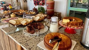 Un bufé de desayuno con panes, pasteles y un pastel sobre una encimera de granito.