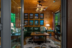 A cozy living room with a green leather sofa, a wooden coffee table, and framed pictures on the wall.