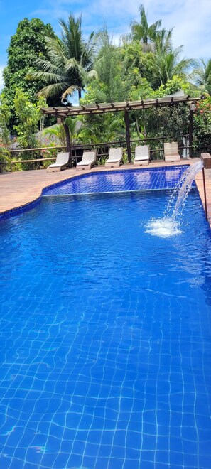 A clear blue pool with a wooden deck and lounge chairs. - Pousada Barra Trip (Maraú)
