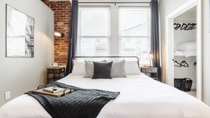 Un dormitorio moderno con una cama grande, una pared de ladrillo y vistas a través de la ventana.
