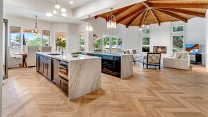 Una cocina amplia con una isla grande, suelo de parqué y techo alto con vigas a la vista.