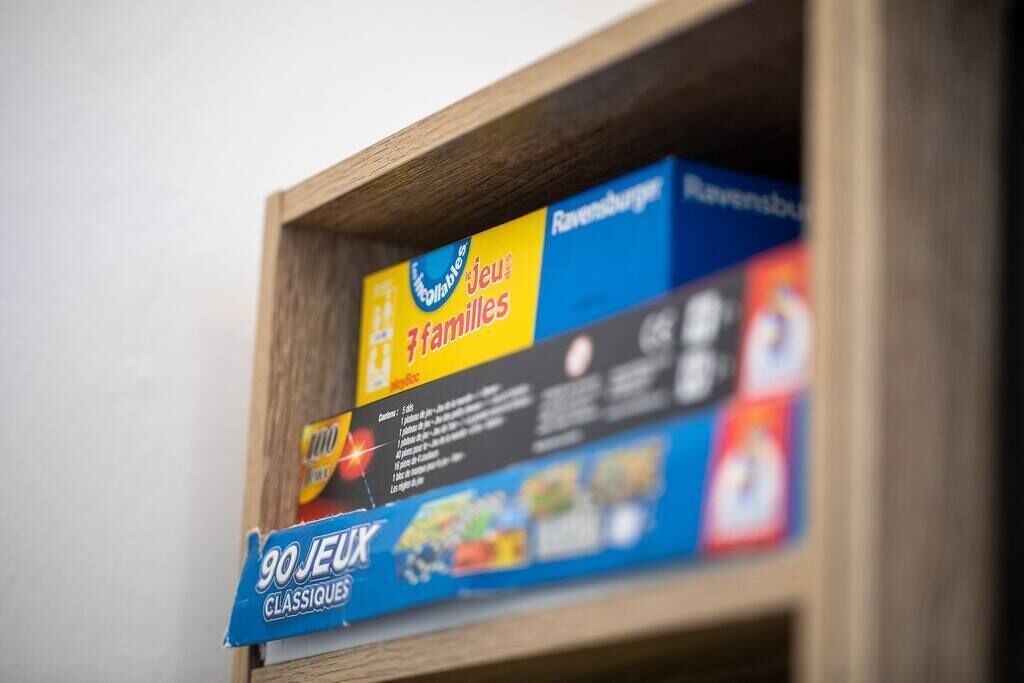 A wooden shelf with three board games: "Jeu de Familles," "Ravensburger," and "90 JEUX CLASSIQUES."