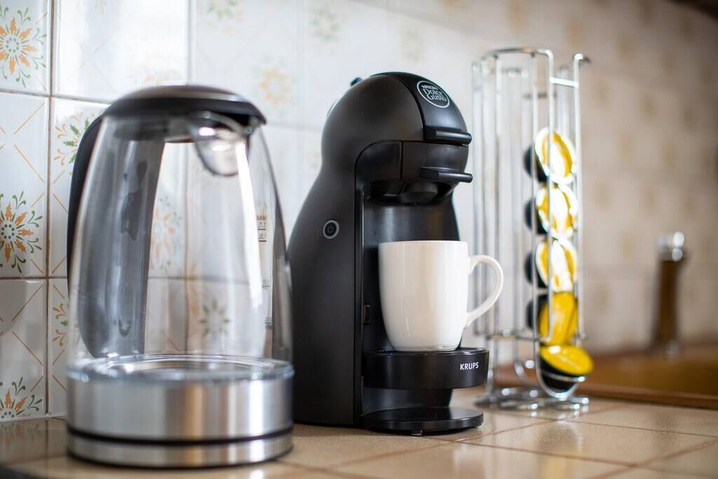 Une machine à café, une verseuse en verre et une tasse sur un plan de travail de cuisine.