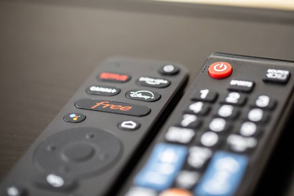 Dos controles remotos, uno con un botón de encendido rojo y otro con teclado numérico.