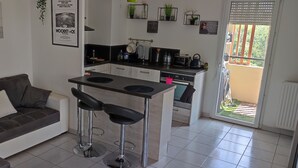 Een compacte leefruimte met een kitchenette, een bank en een kleine eethoek.
