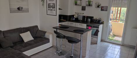 A compact living space with a kitchenette, a sofa, and a small dining area.