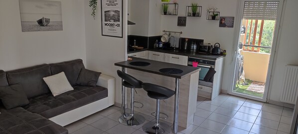 Um espaço compacto para viver, com cozinha compacta, sofá e pequena área de refeições.