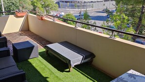 Een balkon met tuinmeubilair, een tafeltje en plantenpotten.