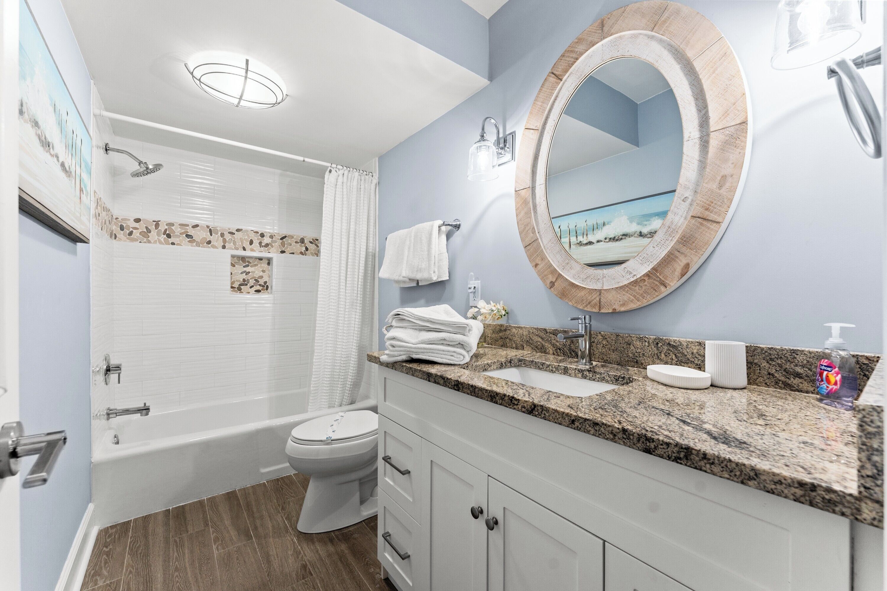 A bathroom with a bathtub, toilet, sink, and a mirror with a wooden frame.