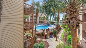 A pool area with a view of a building, a palm tree, and a staircase leading to a balcony. - Anchorage I & II by Elliott Beach Rental (Myrtle Beach)