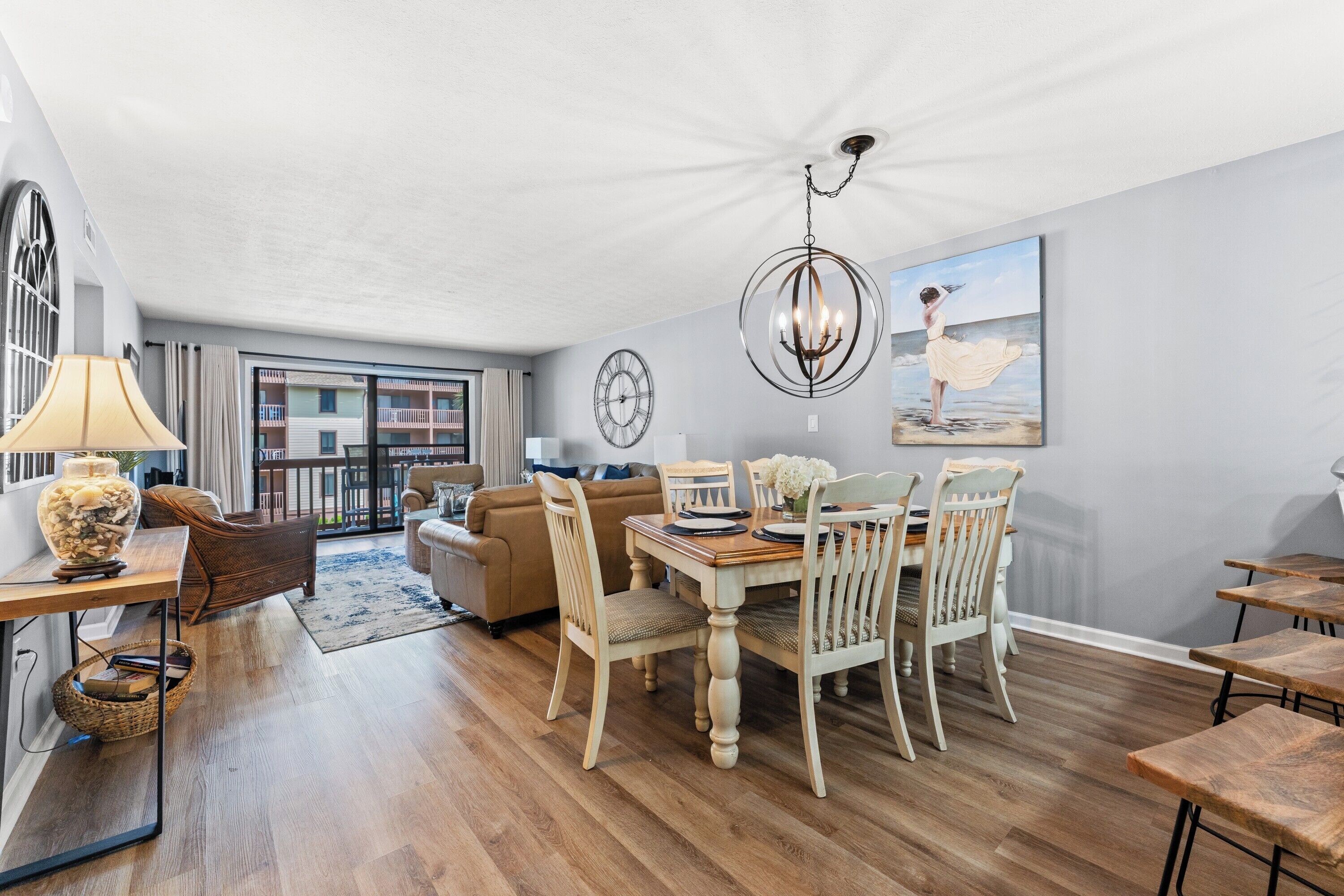A dining area with a wooden table and chairs, a chandelier, and a painting on the wall.