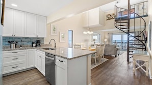 A modern kitchen with white cabinets, a granite countertop, and a built-in dishwasher. - Anchorage I & II by Elliott Beach Rental (Myrtle Beach)