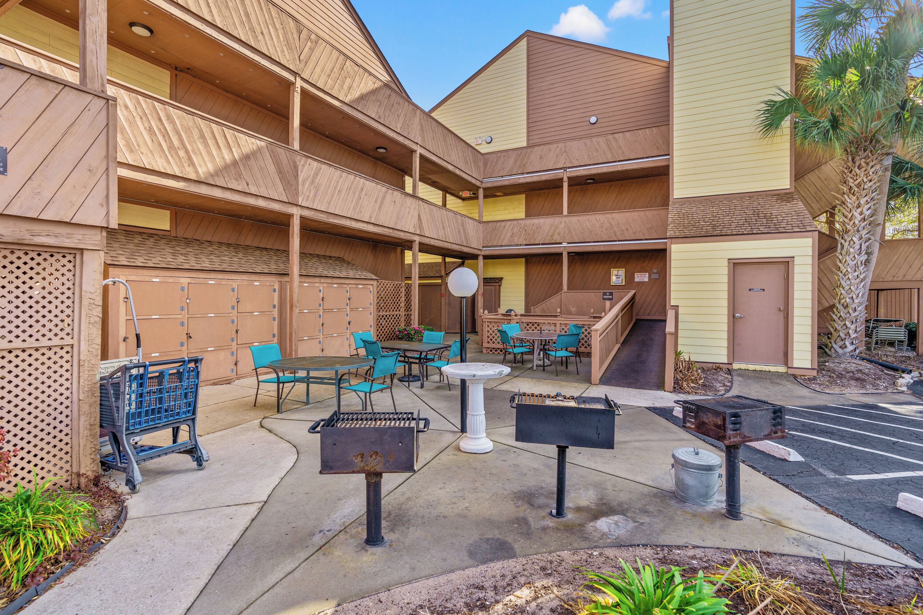 A courtyard with outdoor seating, a barbecue grill, and a covered area with lockers.