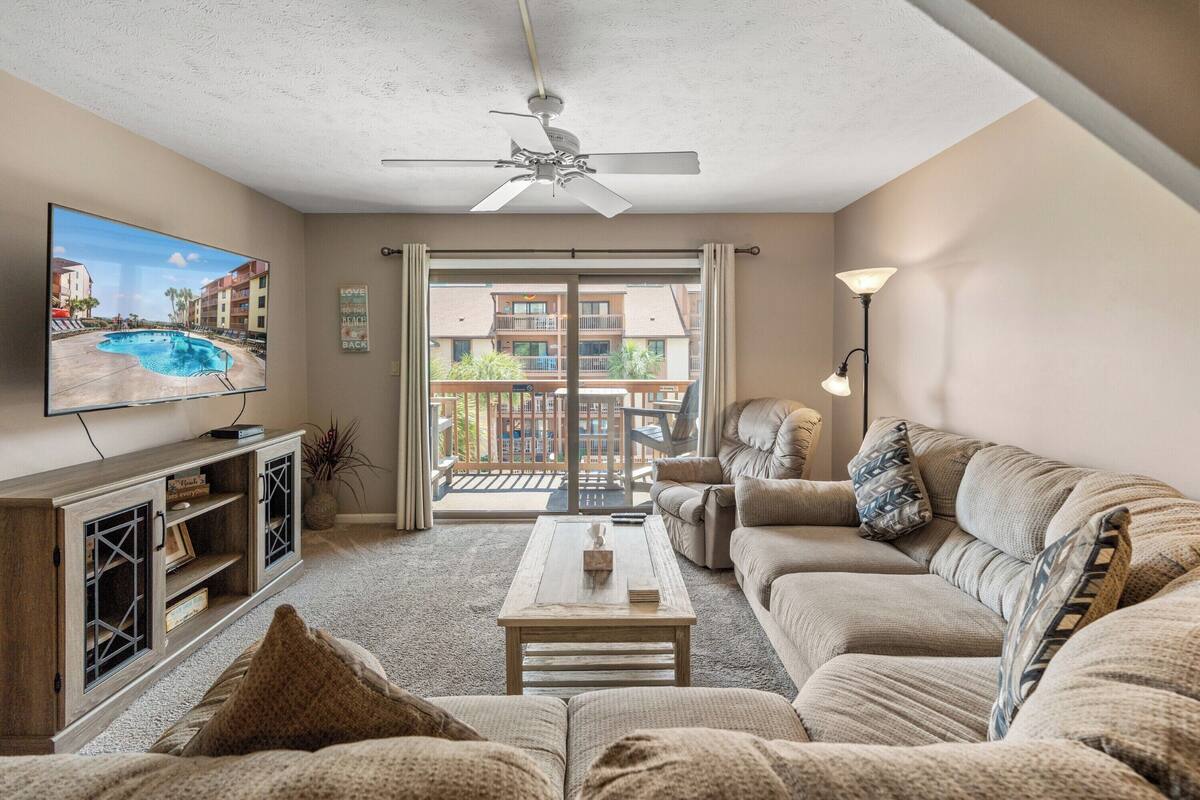 A living room with a sofa, a coffee table, a TV, and a ceiling fan.