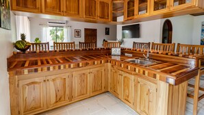 Una cucina con mobili in legno, un'isola centrale con un lavello e un televisore montato a parete.