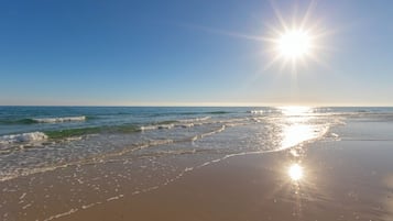 A beach with waves and a bright sun.