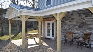 A covered patio area with a picnic table and two wooden chairs.