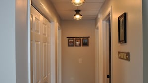 A hallway with wooden flooring, white doors, and a ceiling light fixture.