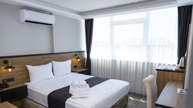 Una habitación de hotel con cama, mesitas de noche, escritorio y silla.